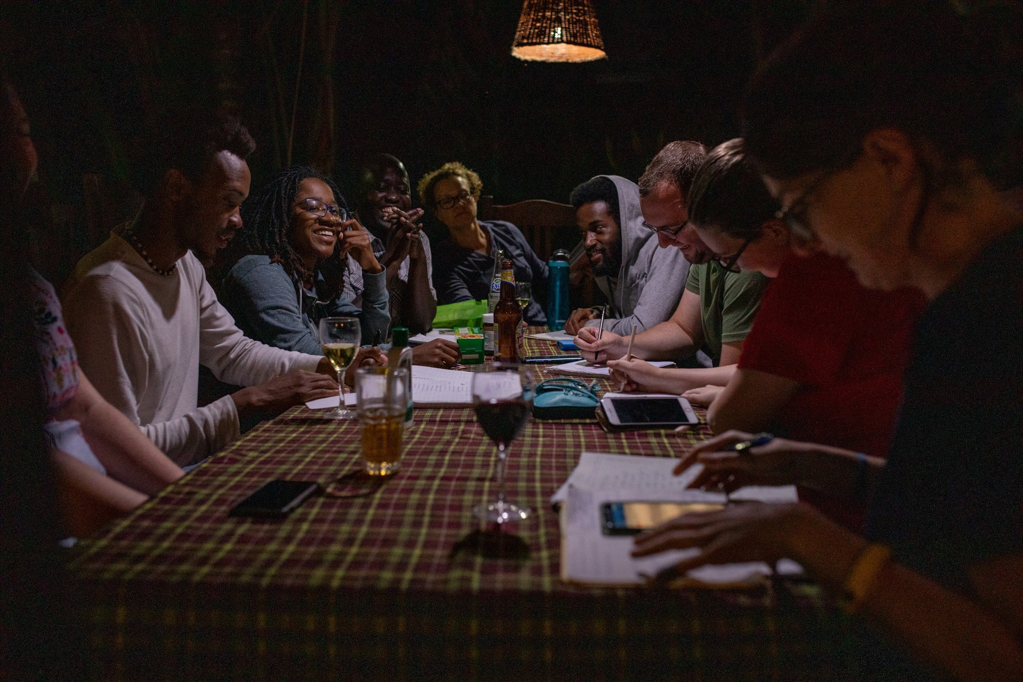 A group of people sitting around a table with drinks and writing implements