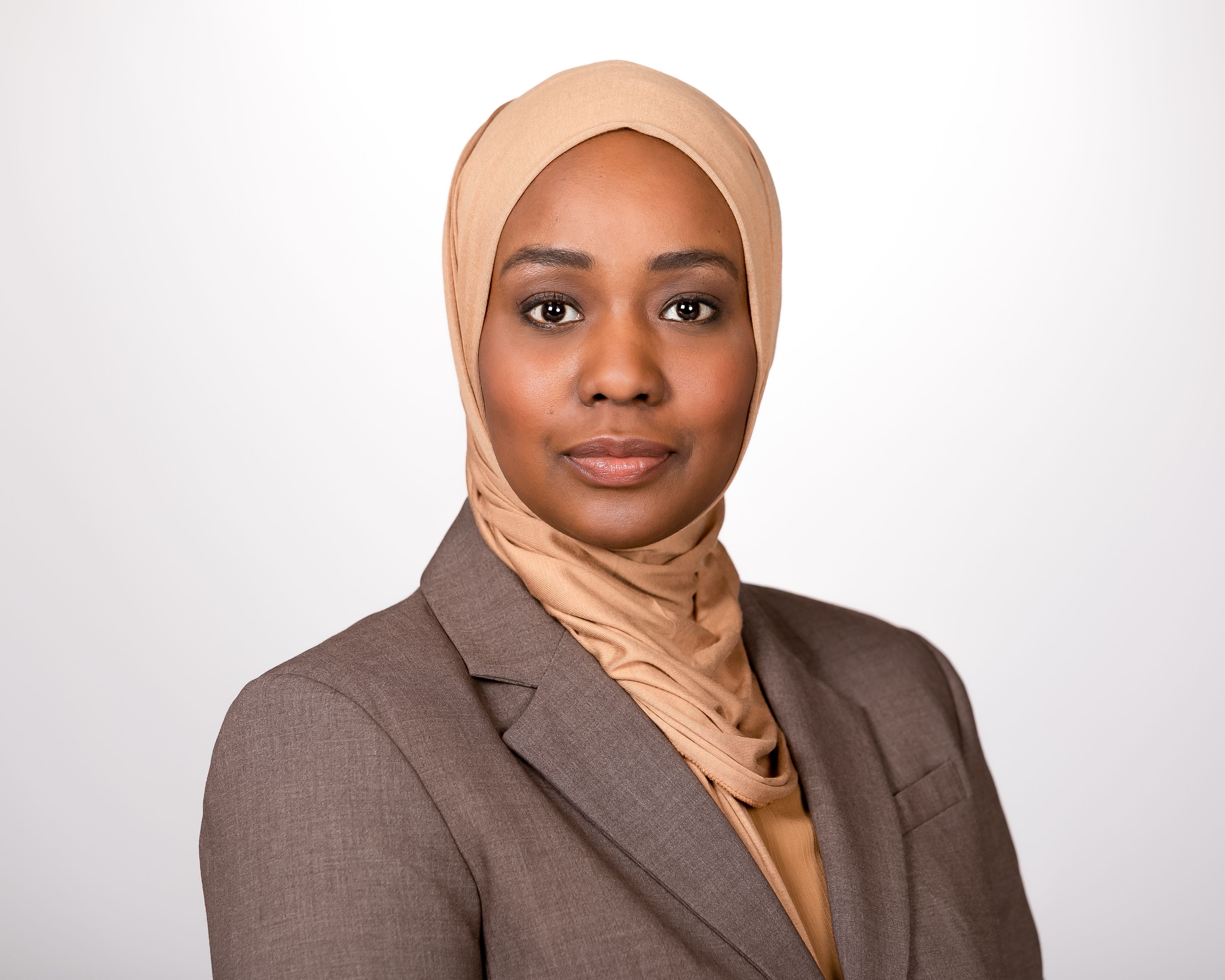 Dr. Hassaballa is posed wearing a tan hijab and gray suit